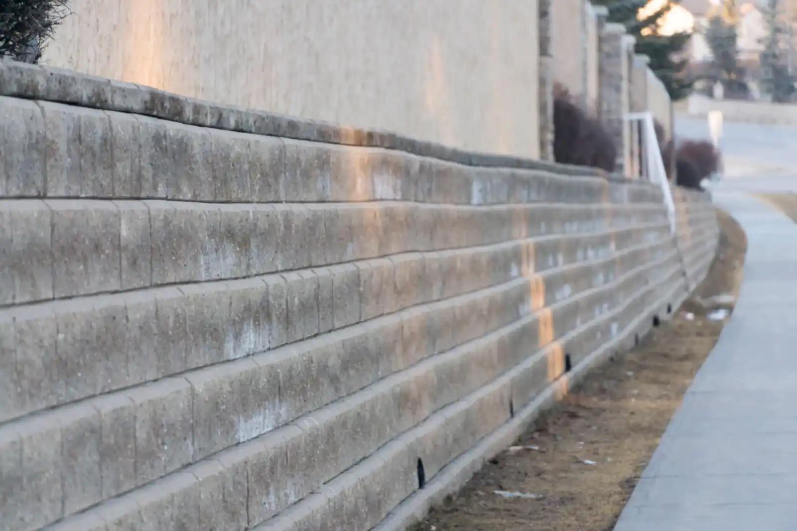 Long block retaining wall with drain outlets running beside a sidewalk
