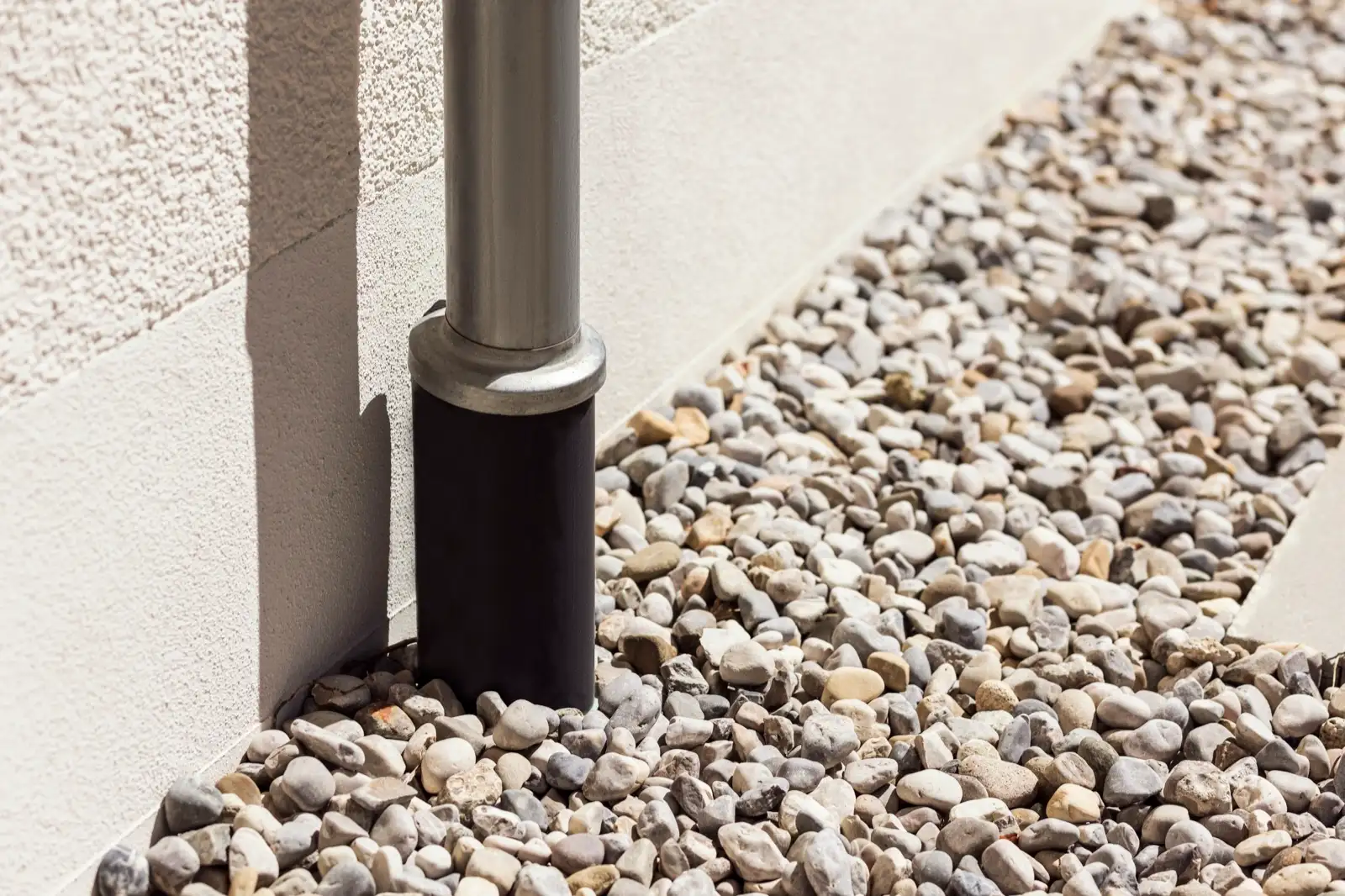 Drain rock along a wall with a downspout running into a buried drain pipe