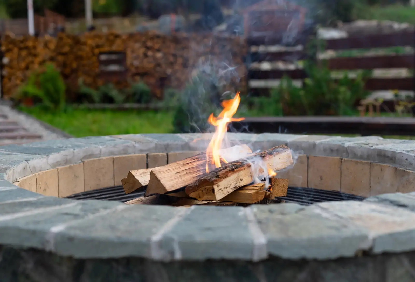 Round block fire pit with a stone cap in a backyard
